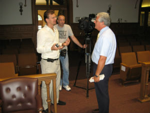 Former Mayor Charles Brunner (far right) being questioned about Madonna at City Hall by a Ukrainian video team